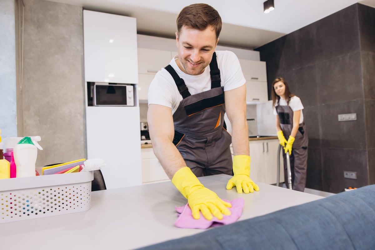 Professional cleaning team in uniforms cleaning kitchen with yellow gloves