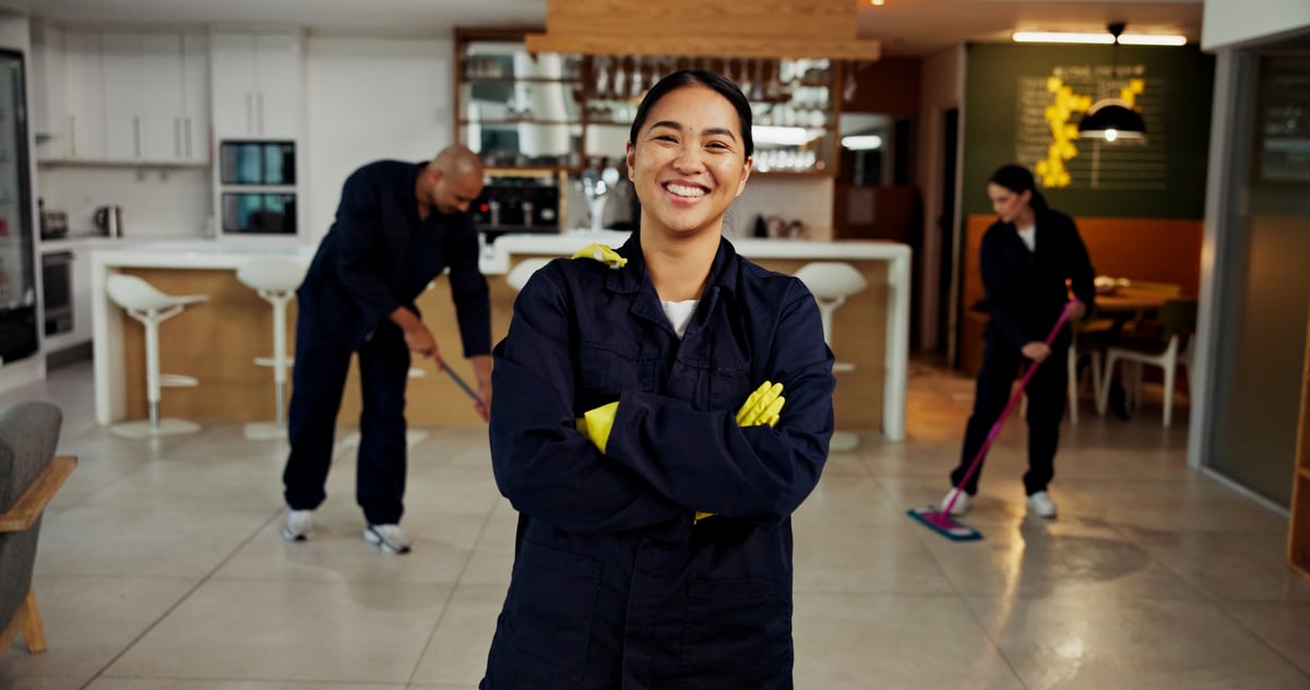 Woman, portrait and janitor with smile for maintenance job, hygiene and arms crossed with team in uniform