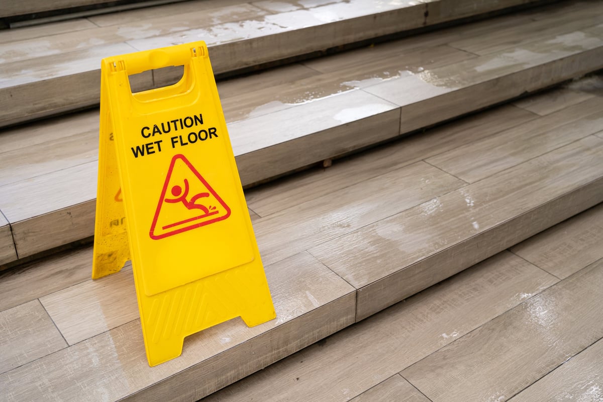 Yellow Caution slippery wet floor sign on the wet ground. Safety Warning in Public Area.