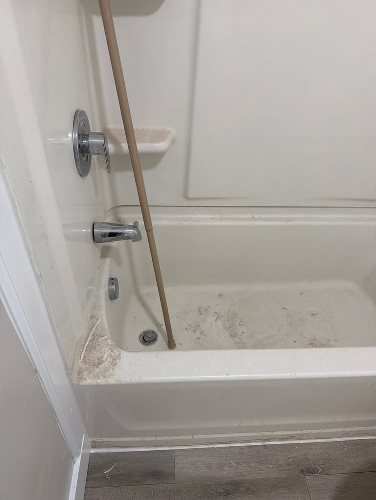 Empty bathtub with chrome fixtures and wooden rod resting diagonally across the tub